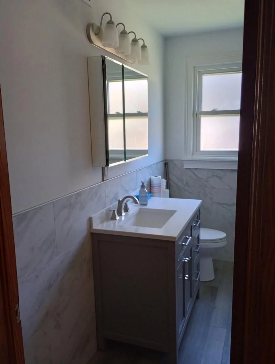 Bathroom remodel with marble tile wainscoting, new vanity with quartz top, and chrome fixtures
