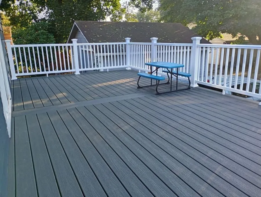 Large gray composite deck surface with white vinyl railing and outdoor furniture
