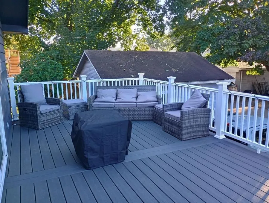 Large composite deck with white vinyl railing, outdoor sectional furniture and covered grill