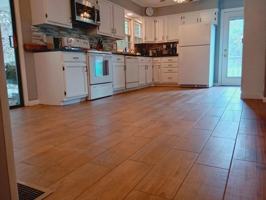 Completed kitchen remodel by American Remodeling and Construction — white cabinets, wood-look tile floor