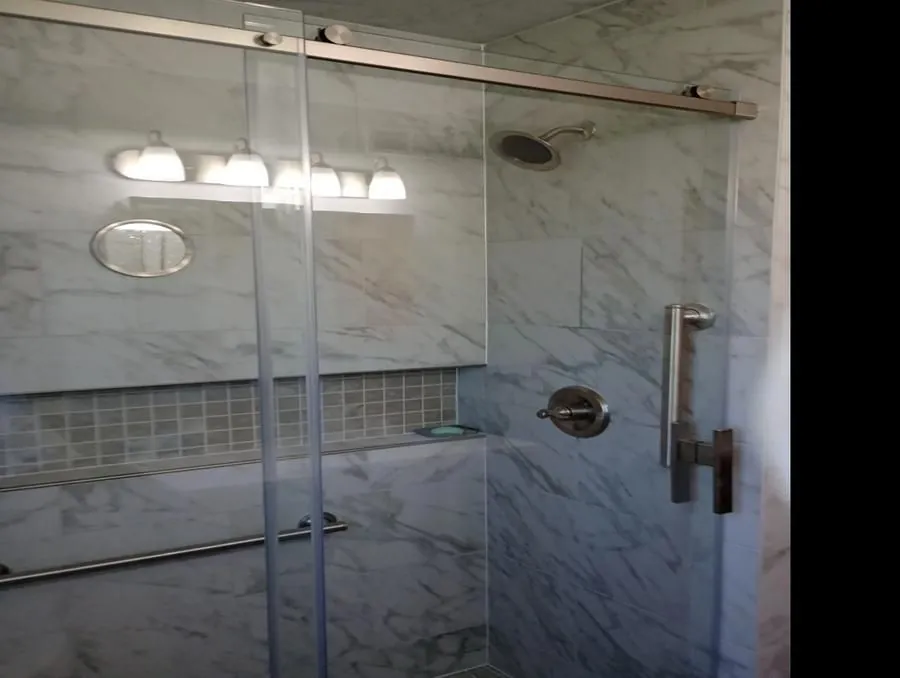 Walk-in shower with full marble tile surround, frameless glass sliding door, and rain showerhead