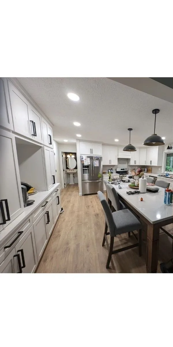 Kitchen after remodel — white shaker cabinets, hardwood floors, pendant lights